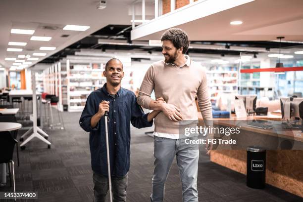 mittlerer erwachsener sehbehinderter mann, der sich mit einem freund an der universität unterhält - blindness stock-fotos und bilder