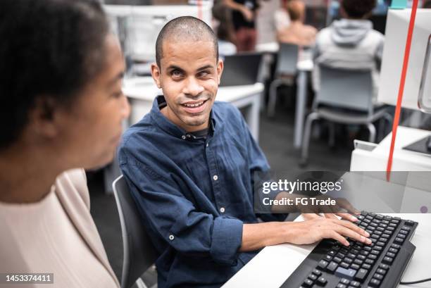 mature woman support university student (or worker) with visually impaired to use computer at library - acesso para deficientes imagens e fotografias de stock