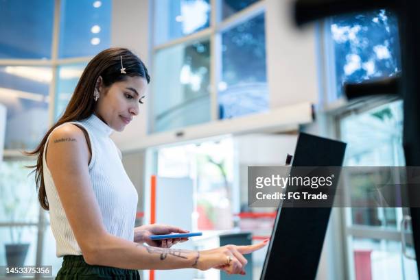 mujer joven que usa la máquina tecnológica ingreso a la universidad - tótem fotografías e imágenes de stock