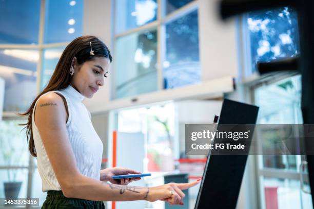 young woman using tech machine university entrance - self service stock pictures, royalty-free photos & images
