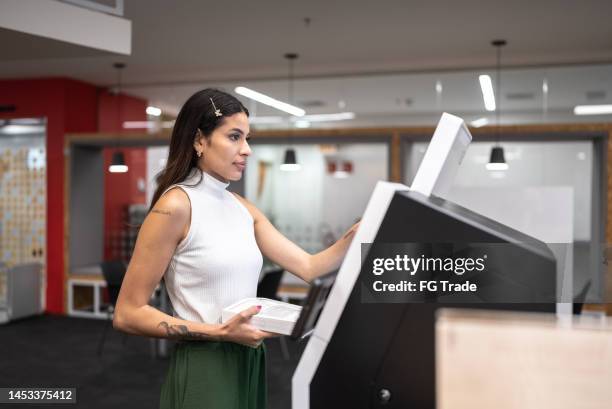 young woman searching for a book in the library system at university - totem pole stock pictures, royalty-free photos & images