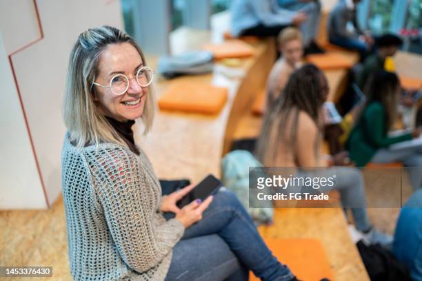 portrait of a mature woman using mobile phone at university auditorium - older woman colored hair stock pictures, royalty-free photos & images