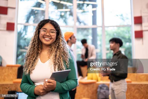 portrait of a young student woman holding a digital tablet at university auditorium - high school student stock pictures, royalty-free photos & images