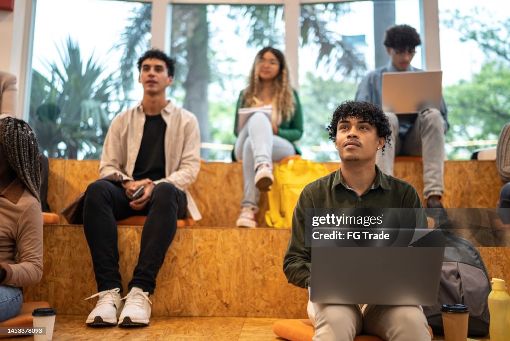 Young student man using laptop while watch class at university auditorium