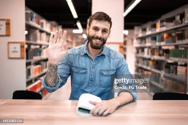 estudiante medio haciendo una videollamada en la biblioteca de la universidad - punto de vista de una cámara fotografías e imágenes de stock