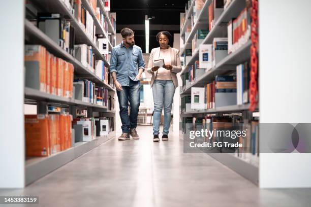 teacher and student walking holding a book at university library - openbare bibliotheek stockfoto's en -beelden