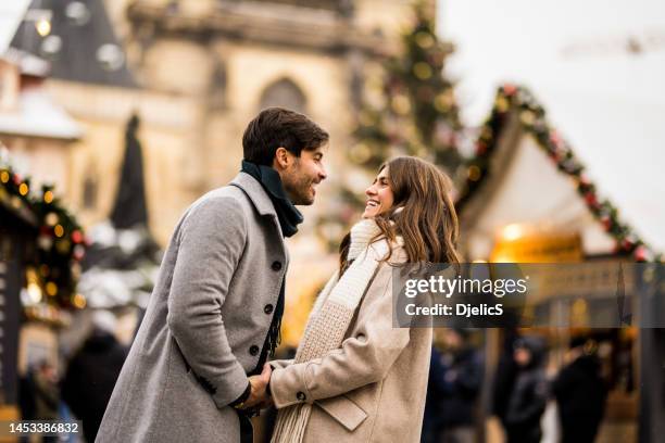 feliz pareja joven divirtiéndose en un día de navidad juntos en la ciudad. - mercado navideño fotografías e imágenes de stock