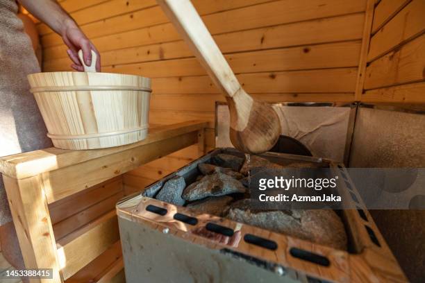 ein mann, der in der finnischen sauna wasser auf heiße steine gießt - finnish culture stock-fotos und bilder