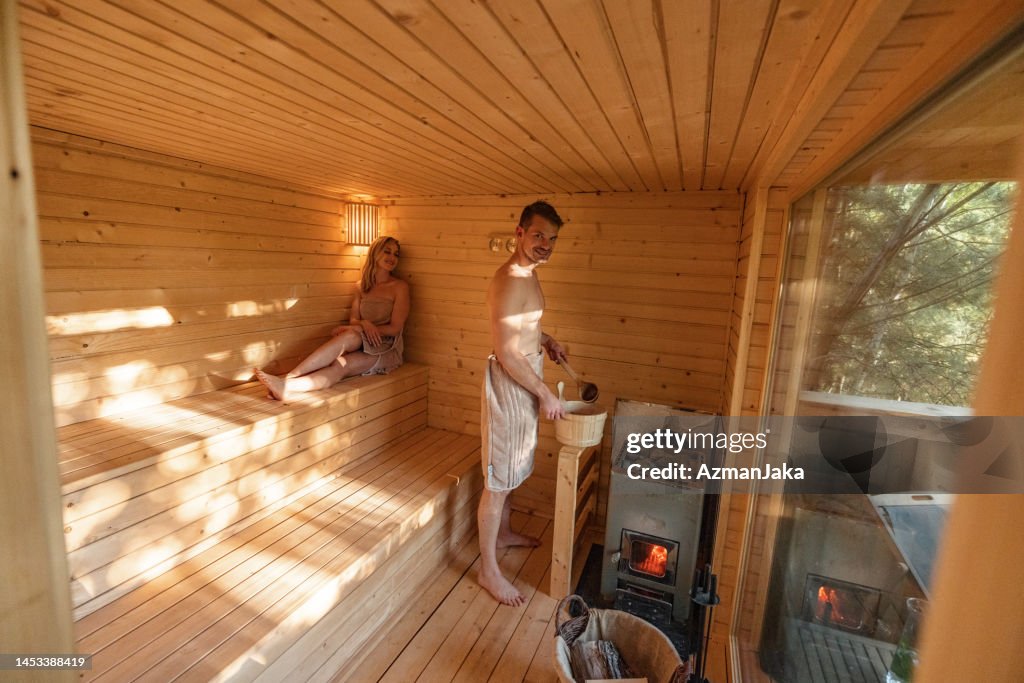 A Man Pouring Water On Hot Stones In Finnish Sauna