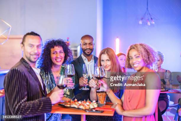 group of businesspeople smiling for a camera during their celebration at a bar - corporate celebration imagens e fotografias de stock