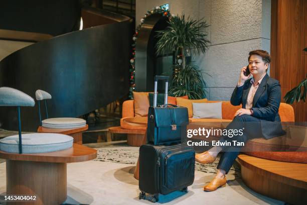 asian chinese businesswoman talking on the smart phone at hotel lobby sitting on sofa - star style lounge imagens e fotografias de stock