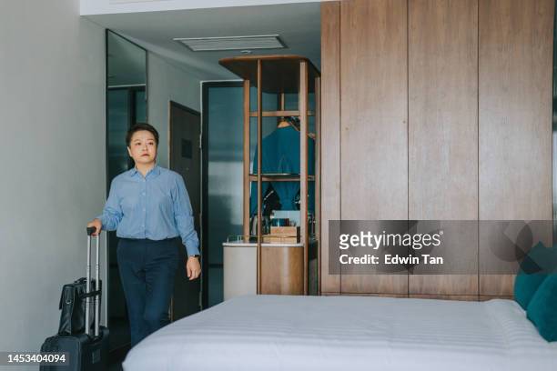 asiatische chinesische geschäftsfrau checkt im hotelzimmer mit koffer ein - asian man suite stock-fotos und bilder