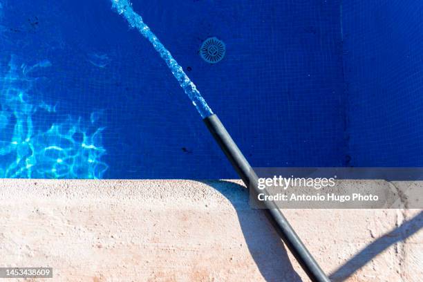 water hose filling a swimming pool. - filling stock-fotos und bilder