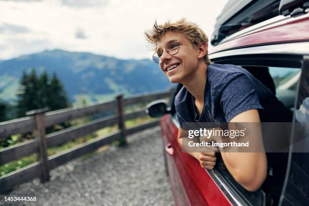 teenager schaut aus dem auto, das an der straße in den hohen österreichischen alpen geparkt ist - boy with car stock-fotos und bilder