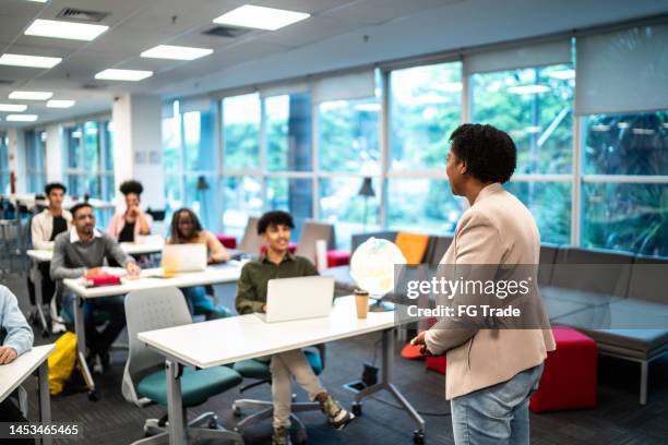 mature teacher woman talking to students during class at university - student public speaking stock pictures, royalty-free photos & images