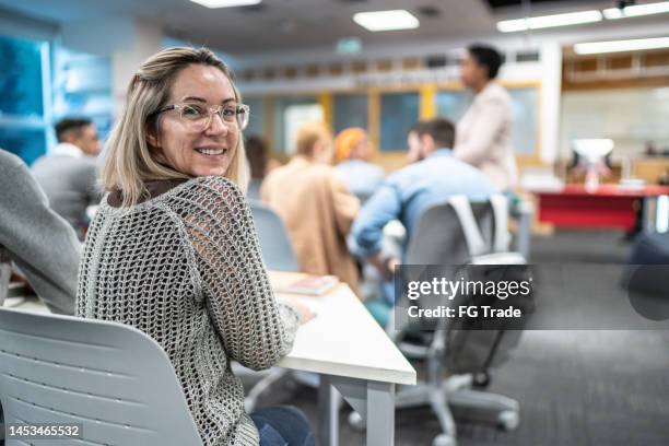 porträt einer reifen frau im klassenzimmer der universität - attending stock-fotos und bilder