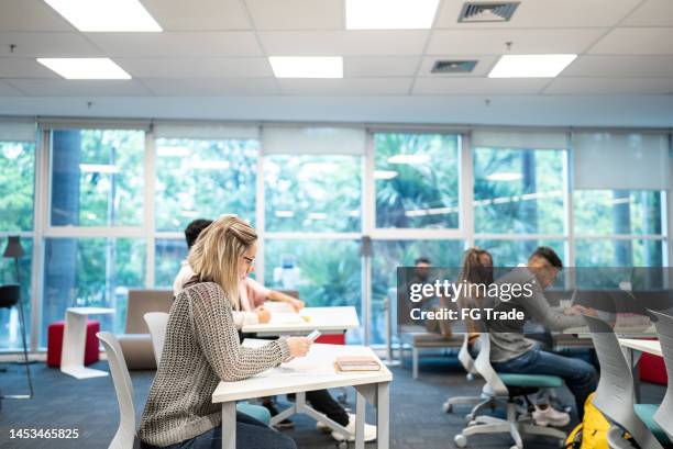 university student woman using mobile phone at university classroom - community college stockfoto's en -beelden