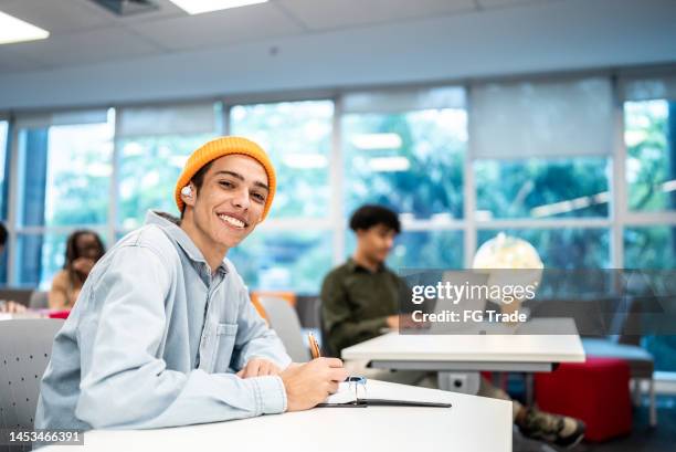 portrait of a young university student man writing at university classroom - laatstejaars high school stockfoto's en -beelden