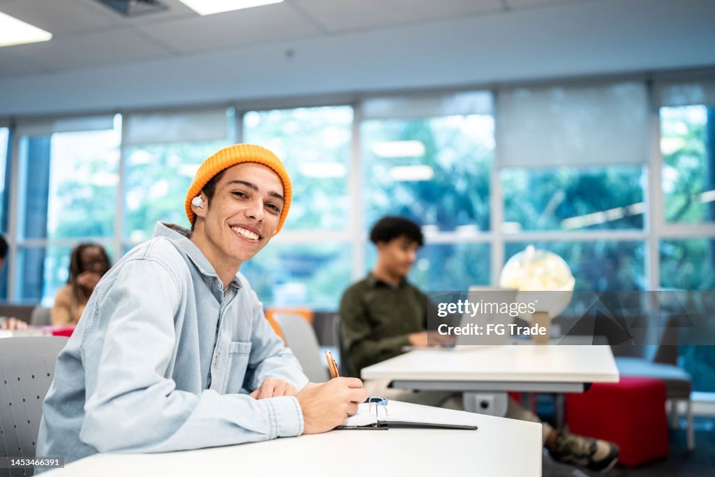 Portrait of a young university student man writing at university classroom