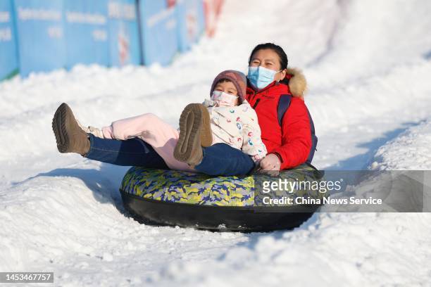Tourists slide on a snow slope with an inflatable circle during an ice and snow festival at the Old Summer Palace on the first day of New Year's Day...