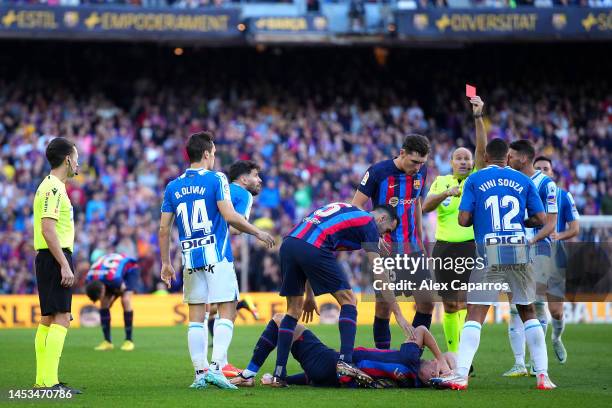 Vinicius Souza of RCD Espanyol receives a red card from Referee Antonio Mateu Lahoz after fouling Robert Lewandowski of FC Barcelona, who lies on the...