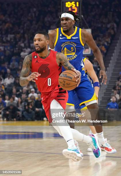 Damian Lillard of the Portland Trail Blazers dribbles past Kevon Looney of the Golden State Warriors during the first quarter of an NBA basketball...