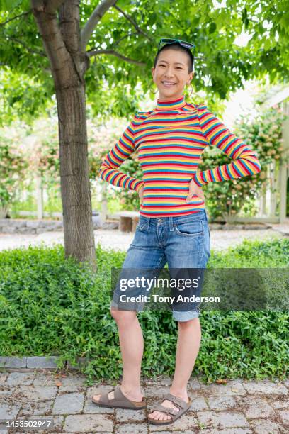 portrait of young woman standing in garden - ladies shorts stock pictures, royalty-free photos & images