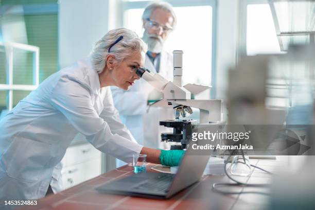 female biochemist using microscope in laboratory - old laboratory stock pictures, royalty-free photos & images