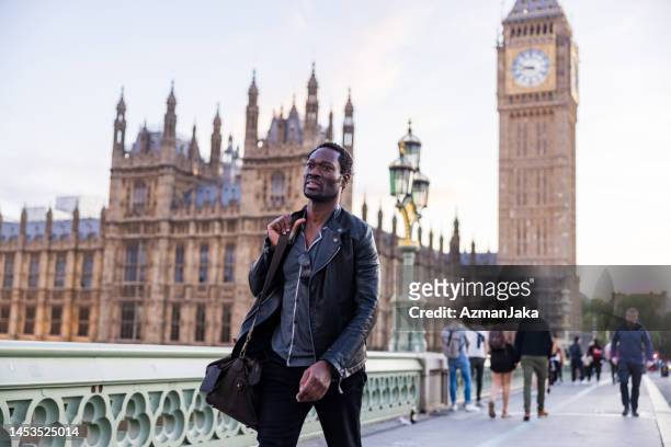 black male traveler walking on a bridge in london - clock tower stock pictures, royalty-free photos & images