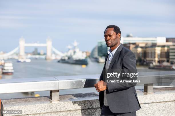 confident mature black male lawyer commuting in the city - man in black suit stock pictures, royalty-free photos & images