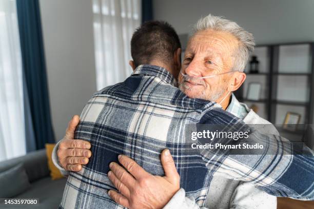 mann und sein älterer vater umarmen sich - old man son stock-fotos und bilder