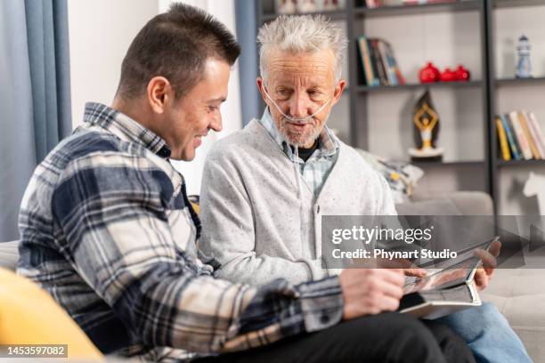 grandad showing his son memories from past - medical oxygen equipment 個照片及圖片檔