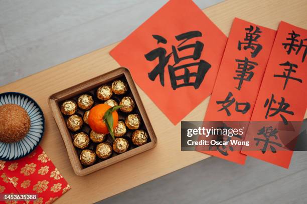 box of traditional chinese treats, fried pile, fai chun and red packets on coffee table - chinese window pattern stockfoto's en -beelden