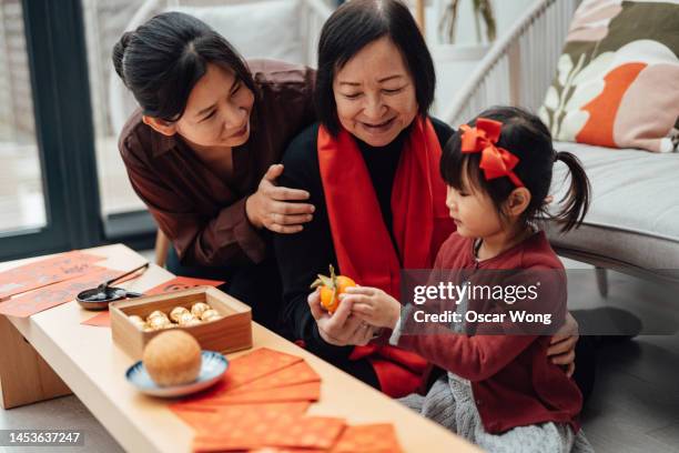 cheerful three-generation asian family celebrating chinese new year at home - hong kong grandmother stock pictures, royalty-free photos & images