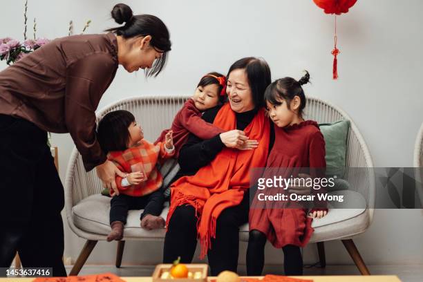 cheerful three-generation asian family celebrating chinese new year at home - chinese culture stock-fotos und bilder