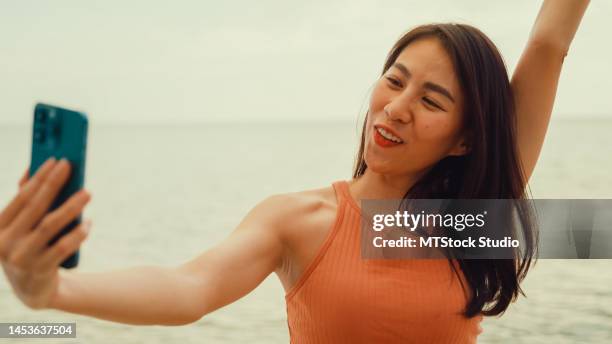 young asian woman using smartphone taking a selfie on tropical beach. - hammamet beach stock pictures, royalty-free photos & images