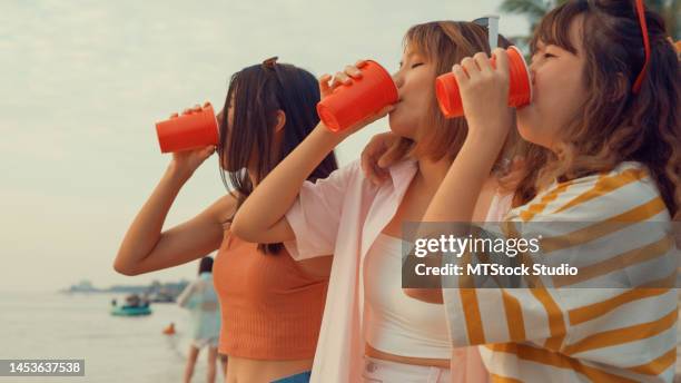 group of young asian women celebrating and drinking alcohol on tropical beach. - asian female friends drinking soda outdoor stock pictures, royalty-free photos & images