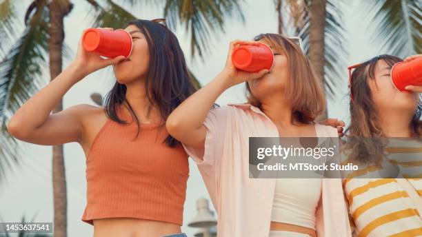 group of young asian women celebrating and drinking alcohol on tropical beach. - asian female friends drinking soda outdoor stock pictures, royalty-free photos & images