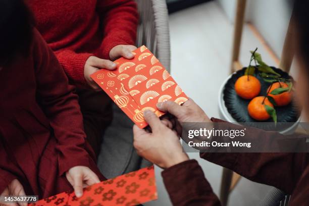 cropped shot of children receiving red envelopes from their parent during chinese new year - wish fotografías e imágenes de stock