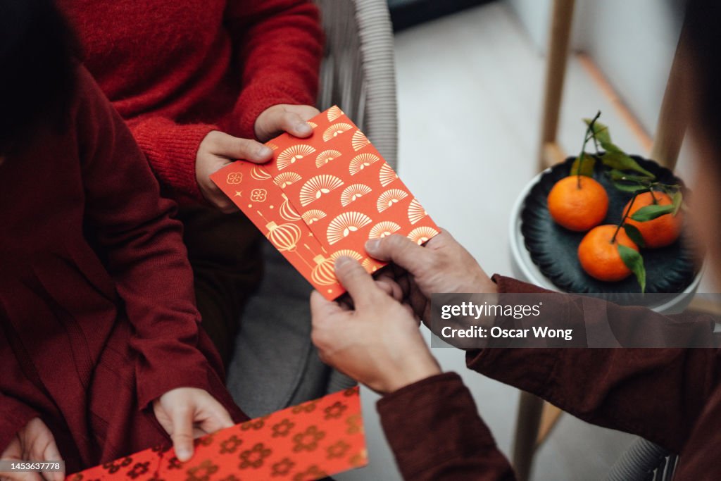 Cropped shot of children receiving red envelopes from their parent during Chinese New Year
