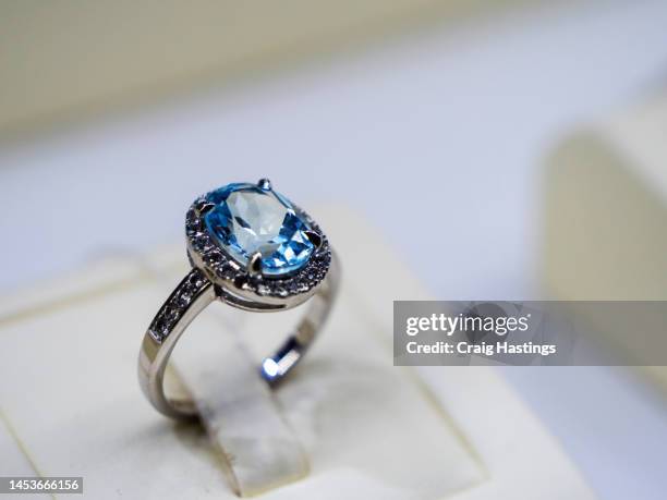 macro close up sapphire & topaz coloured gemstone set rings arranged in a row in jewellery store shop setting. luxury ring display with shining colourful stones and diamonds. high end luxury shopping. - topaz imagens e fotografias de stock