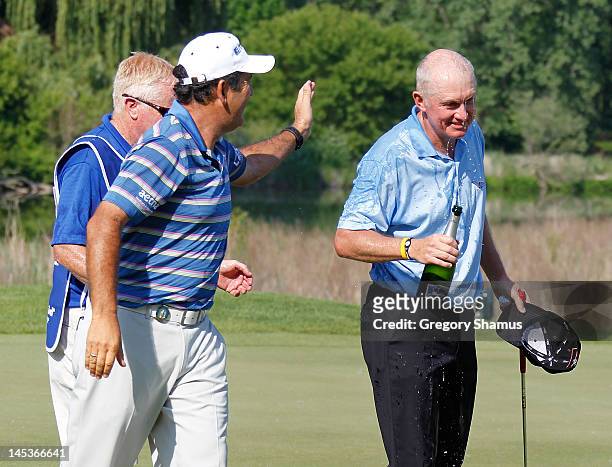 Roger Chapman of England celebrates with champagne with David Frost on the 18th green after winning the 2012 Senior PGA Championship at the Golf Club...
