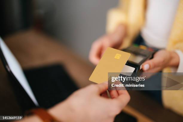 close up photo of woman hands paying with credit card in a home decor store - cartão de crédito imagens e fotografias de stock