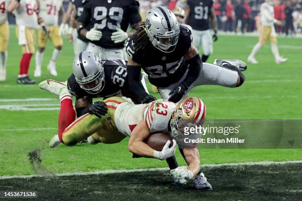 Running back Christian McCaffrey of the San Francisco 49ers scores on a 14-yard touchdown run against cornerback Nate Hobbs and safety Tre'von...