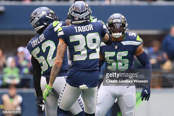Darrell Taylor, Teez Tabor and Jordyn Brooks of the Seattle Seahawks celebrate after a defensive play during the second quarter in the game against...