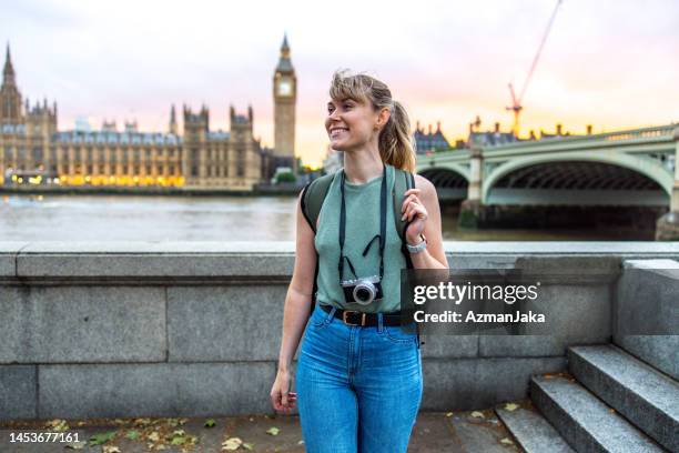 caucasian young adult female tourist smiling as she is exploring london's landmarks - westminster bridge stock pictures, royalty-free photos & images