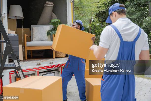 two professional man mover worker courier house mover handover cardboard box in to the truck. - möbelpacker stock-fotos und bilder