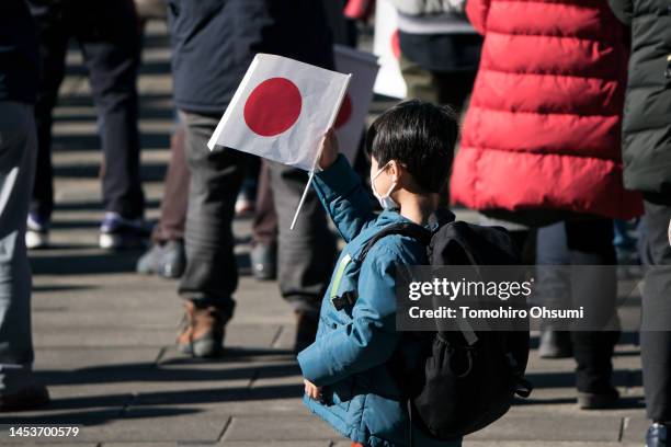 Boy holds a Japanese national flag during the New Year's appearance by the Japanese royal family at the Imperial Palace on January 2, 2023 in Tokyo,...