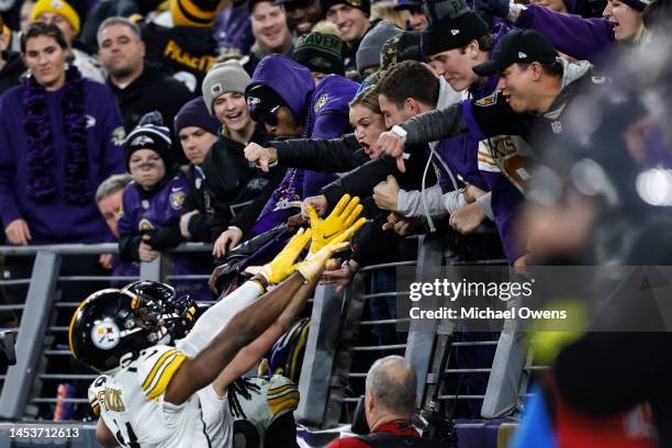 George Pickens, Pat Freiermuth and Najee Harris of the Pittsburgh Steelers celebrate after Harris scored a touchdown as fans react during an NFL...