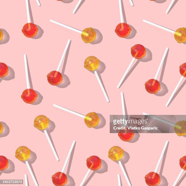 seamless pattern of red and yellow lollipops against pink background - lollipop fotografías e imágenes de stock